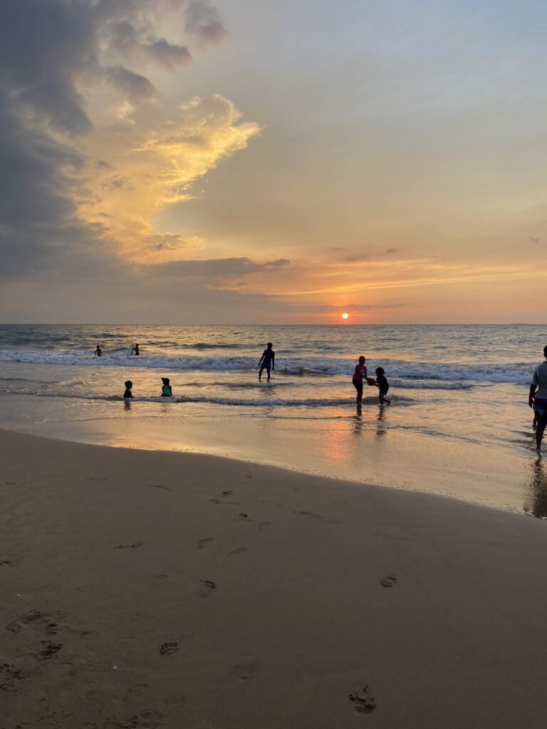 solnedgang på en strand på sri lanka hvor mennesker bader